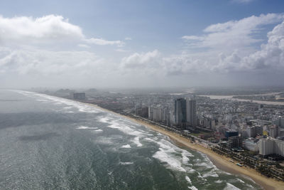 Aerial view of city by sea against sky