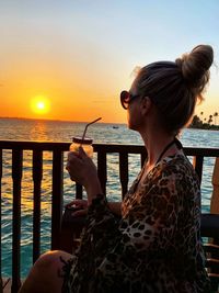 Woman looking at sea against sky during sunset