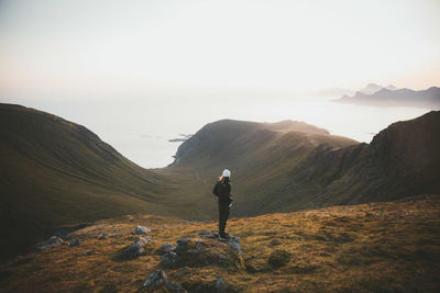 Rear view of man standing on mountain against sky