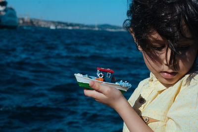 Portrait of boy holding sunglasses against sea