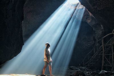 Man standing on rock against sun ray 