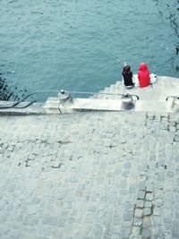 High angle view of friends sitting on steps against lake