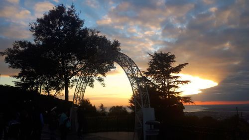 Silhouette trees on field against sky during sunset