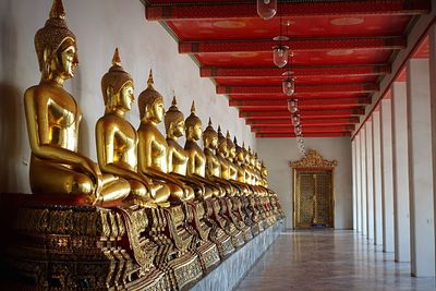 Gold buddha statues in row at wat pho corridor
