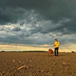 Dog standing on field against sky during sunset