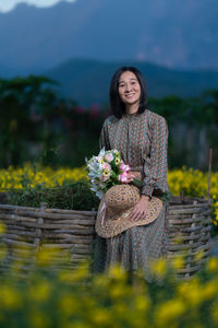 Portrait of a smiling young woman standing against stone wall