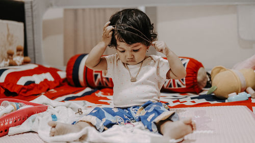 Portrait of little girl playing with her hair on bed at home