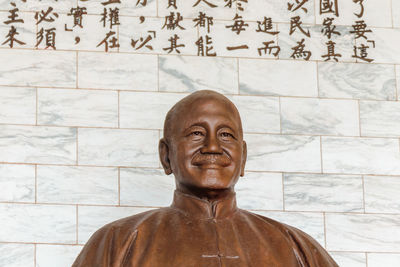 Portrait of smiling statue against wall