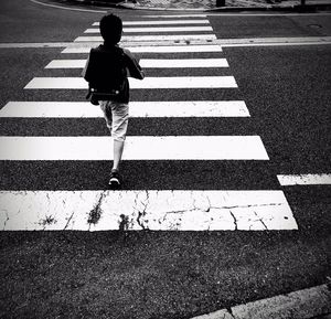 Rear view of boy walking on zebra crossing