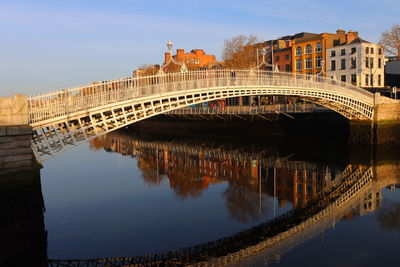 Arch bridge over river against sky in city