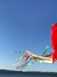 Close-up of multi colored umbrellas against clear blue sky