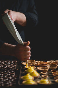 Midsection of chef making pastries with piping bag in bakery