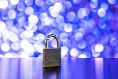 Close-up of padlock on table against defocused lights 