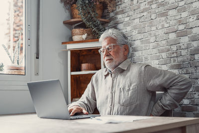 Rear view of woman using laptop at home