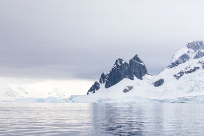 Scenic view of sea and snowcapped mountain against sky