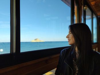 Woman looking at sea seen through window