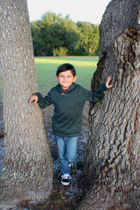 Portrait of teenage boystanding on tree trunk