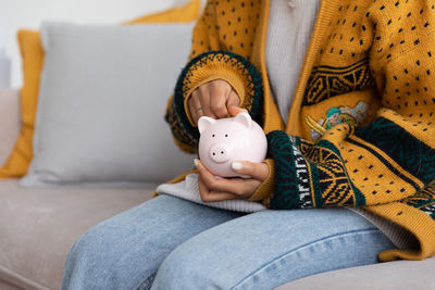 Midsection of woman sitting on sofa at home