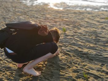 Man crouching on sand at beach