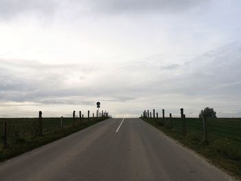 Empty road along landscape against sky