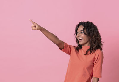 Happy woman standing against pink background