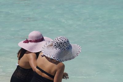 Rear view of women wearing hat against sea