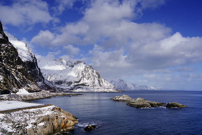 Scenic view of sea by snowcapped mountains against sky