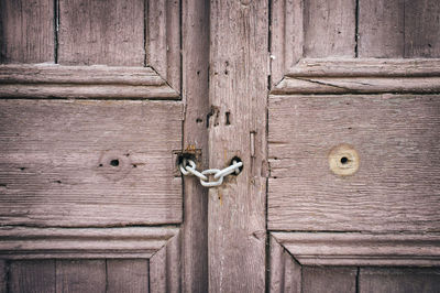 Close-up of chain hanging on wooden door