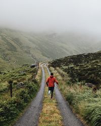 Rear view of woman walking on road against mountain