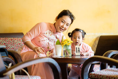 Mother and daughter wearing traditional dress at cafe in hoi an vietnam.