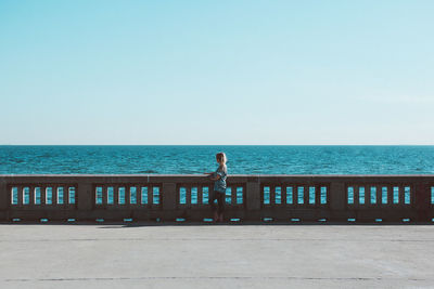 Woman standing against sea and clear sky