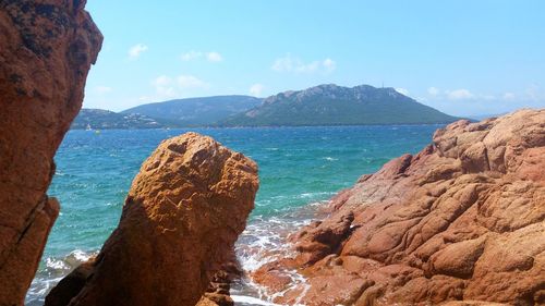 Scenic view of sea by mountains against sky