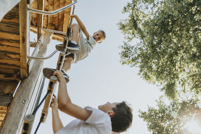 Brothers climbing ladder in public park on sunny day