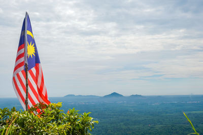 Malaysia flag on landscape against sky in panau hill, kelantan, malaysia.