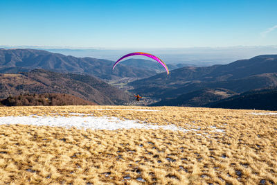 People paragliding against mountain range