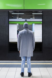 Businessman in long coat standing at railroad station