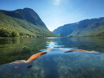 Scenic view of man swimming under water in lake with mountains against sky