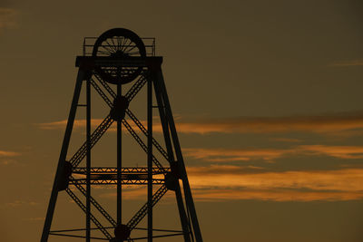 Silhouette of crane against sky at sunset