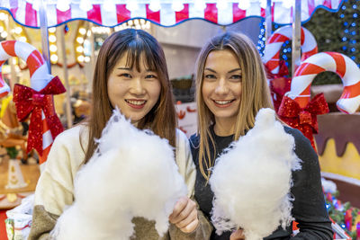 Couple of young multi-ethnic women eating cotton candy at a party. concept of millennial generation