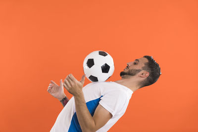 Cropped hand holding soccer ball against yellow background