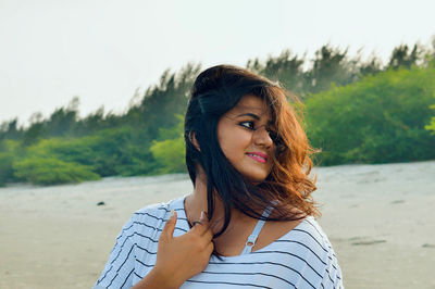 Beautiful woman smiling woman with tousled hair standing at beach