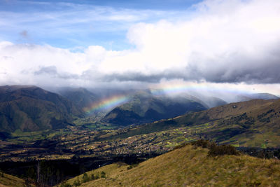 Scenic view of landscape and rainbow  against sky