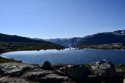 Scenic view of sea and mountains against clear blue sky