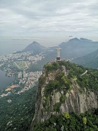 Aerial view of christ the redeemer and buildings against cloudy sky