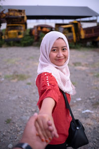 Portrait of smiling young woman holding hand of man on field