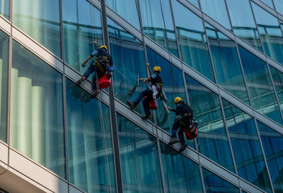 Milan italy march 29 2021  skilled glass cleaners who lower themselves with slings from above