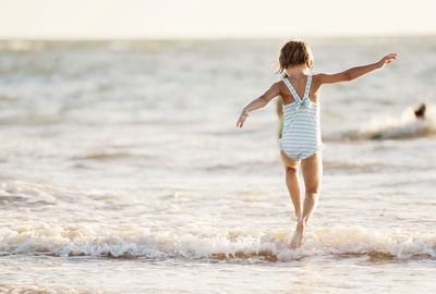 Rear view of girl jumping in sea
