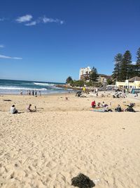 People on beach against clear blue sky