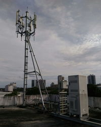 Low angle view of communications tower amidst buildings against sky