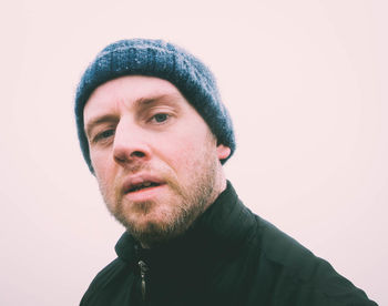 Portrait of bearded young man wearing knit hat against sky